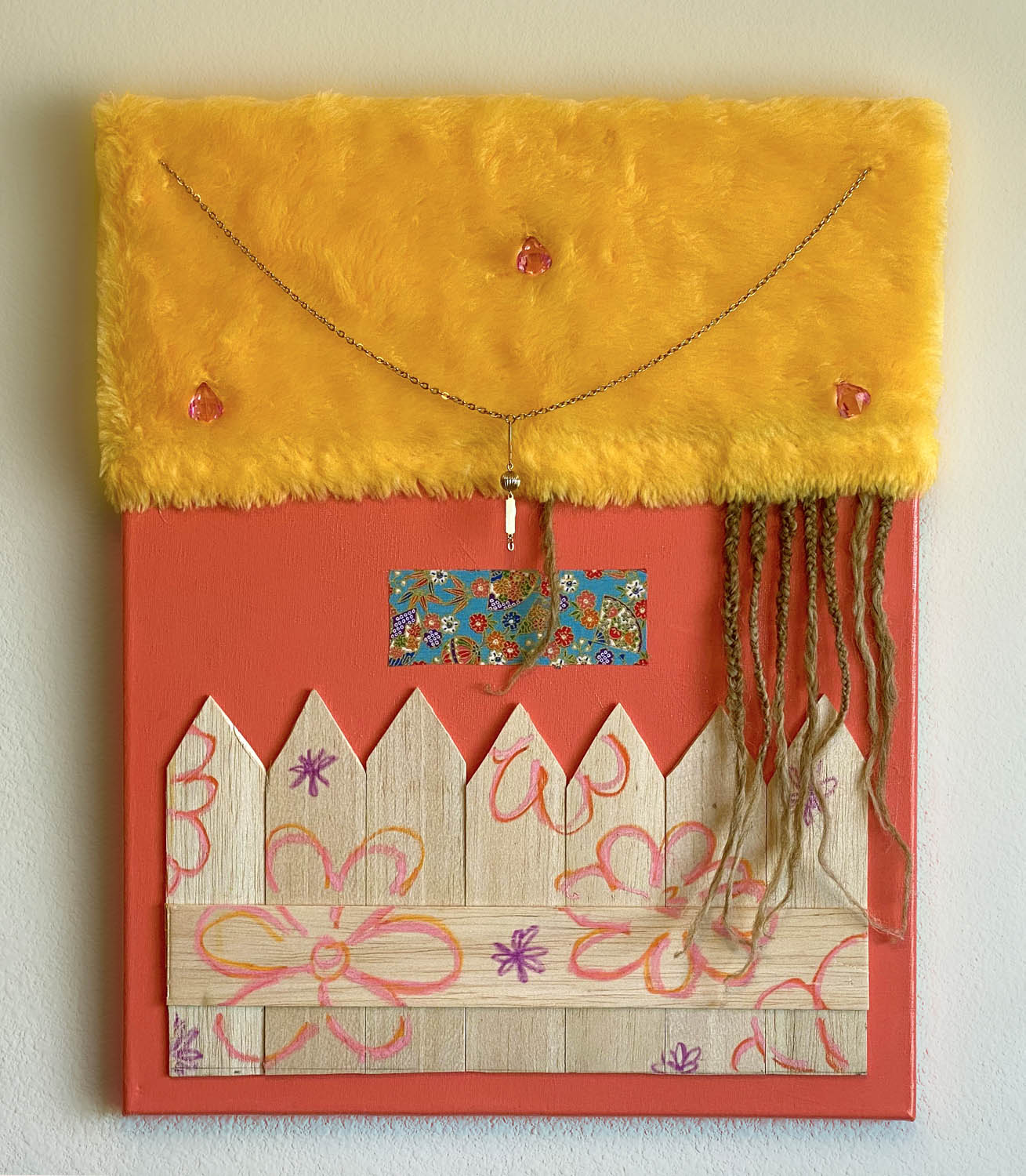 A mixed media piece on a coral colored canvas with fuzzy orange fabric on the top and a wooden fence on bottom that has flowers painted on it. Braided human hair is coming out of the bottom of the fuzzy fabric hanging down over the fence.